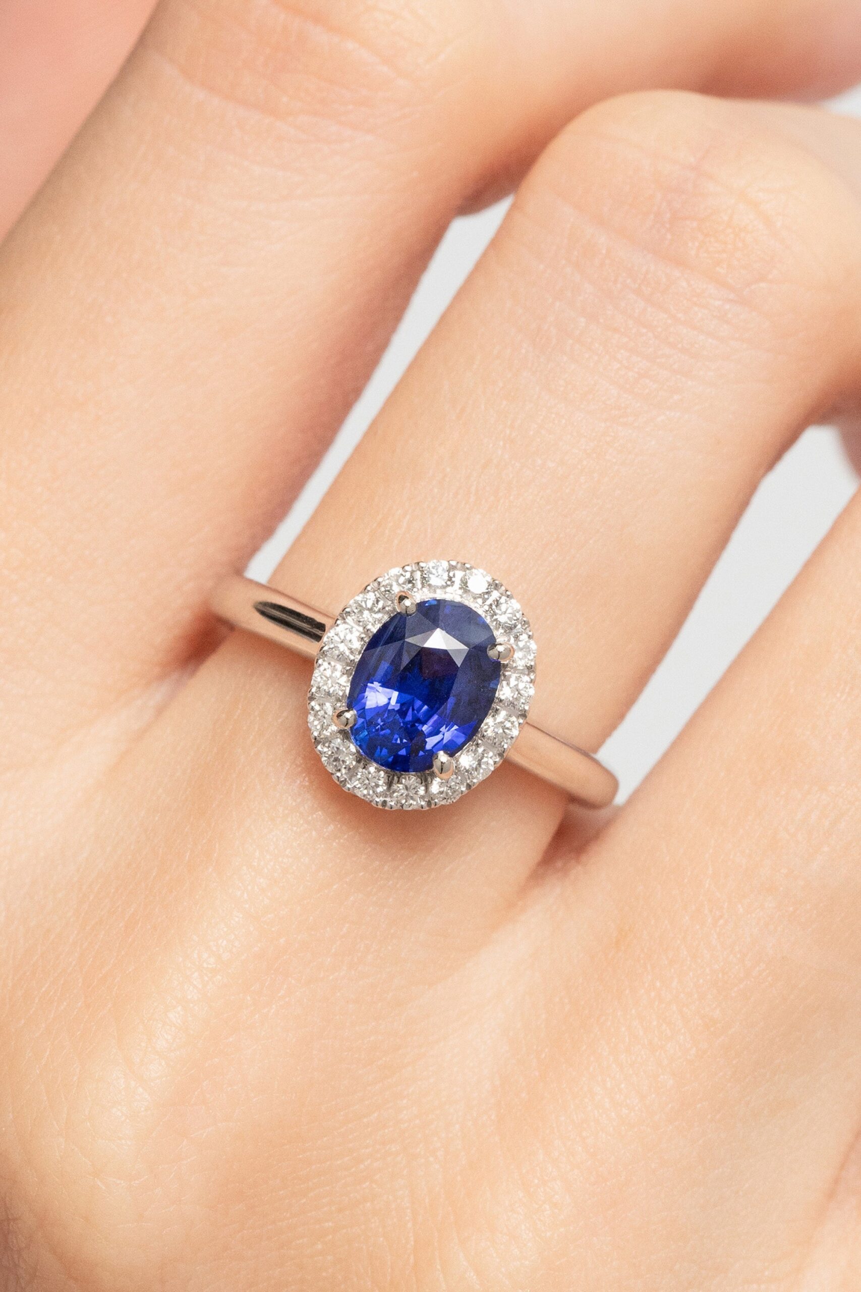 Anillo de compromiso de zafiro azul con halo de diamantes, llevado en el anular — Bonnot Paris